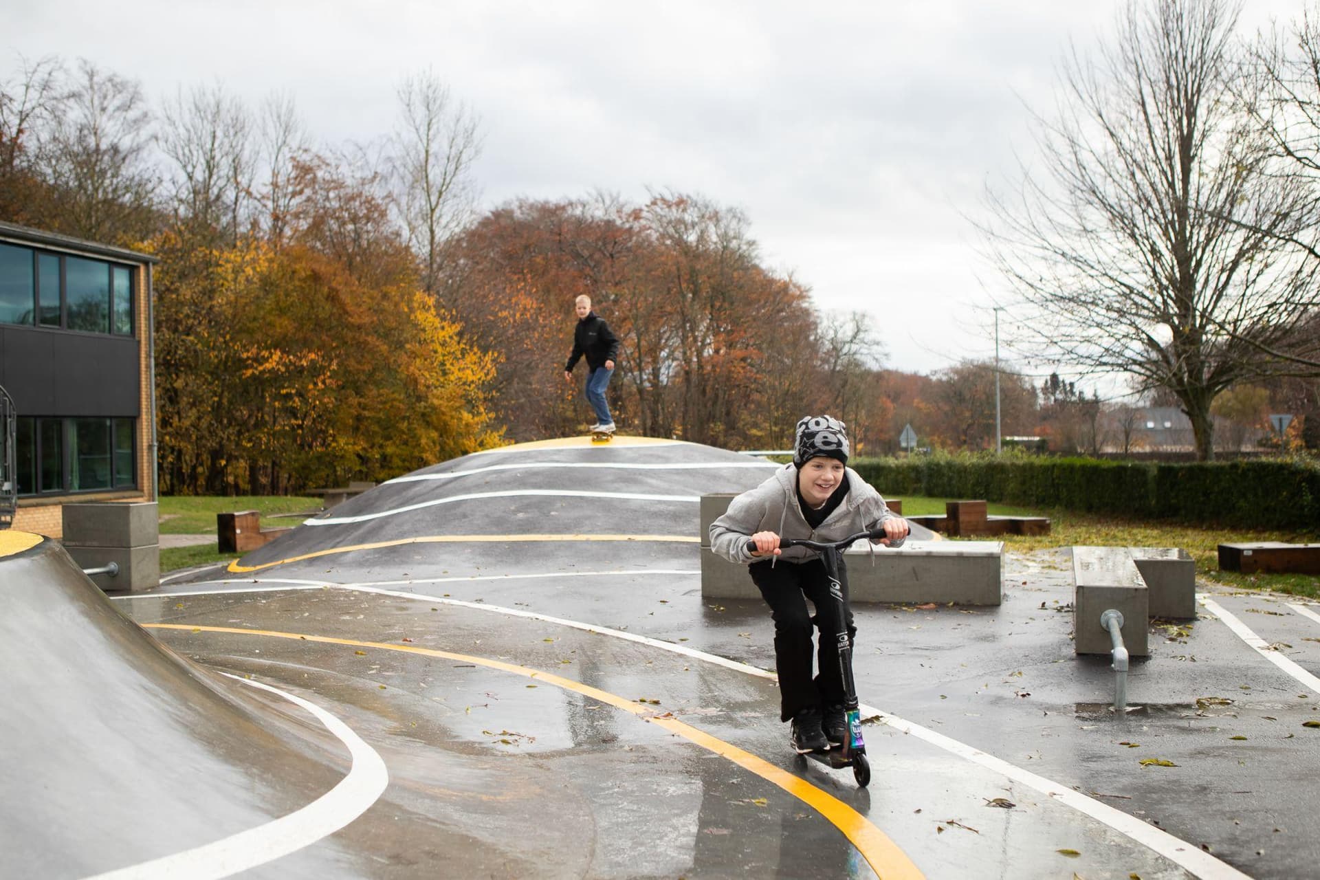 Barn på løbehjul på vådt betoncykelstien med springskanse og modulus i baggrund