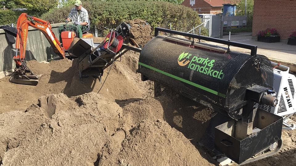 Gravemaskine og læsser arbejder med jordarbejde på byggeplads ved institution