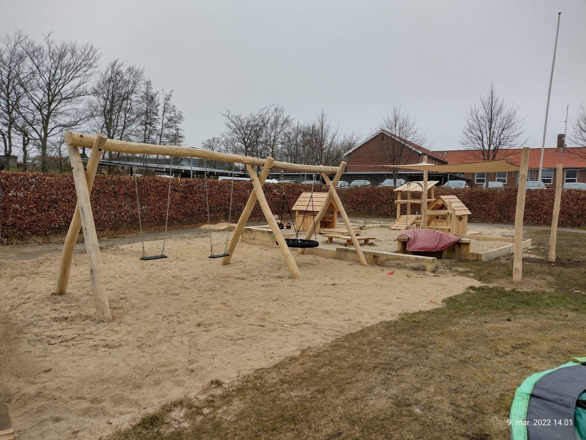 Træ-legeanlæg med gynger, klatrestativ og sandkasse på sandunderlag