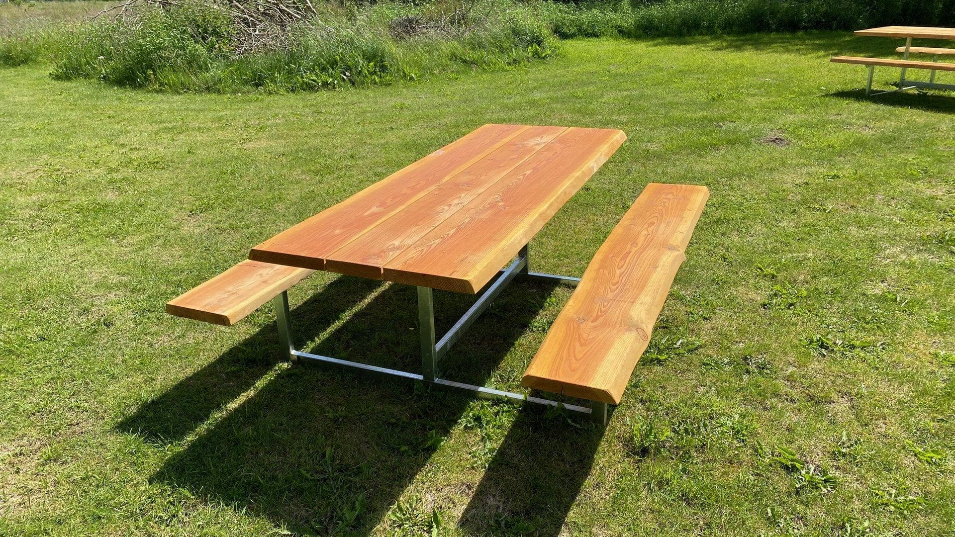 Picnicbord i robinietræ med fastmonterede bænke på grøn græsplæne