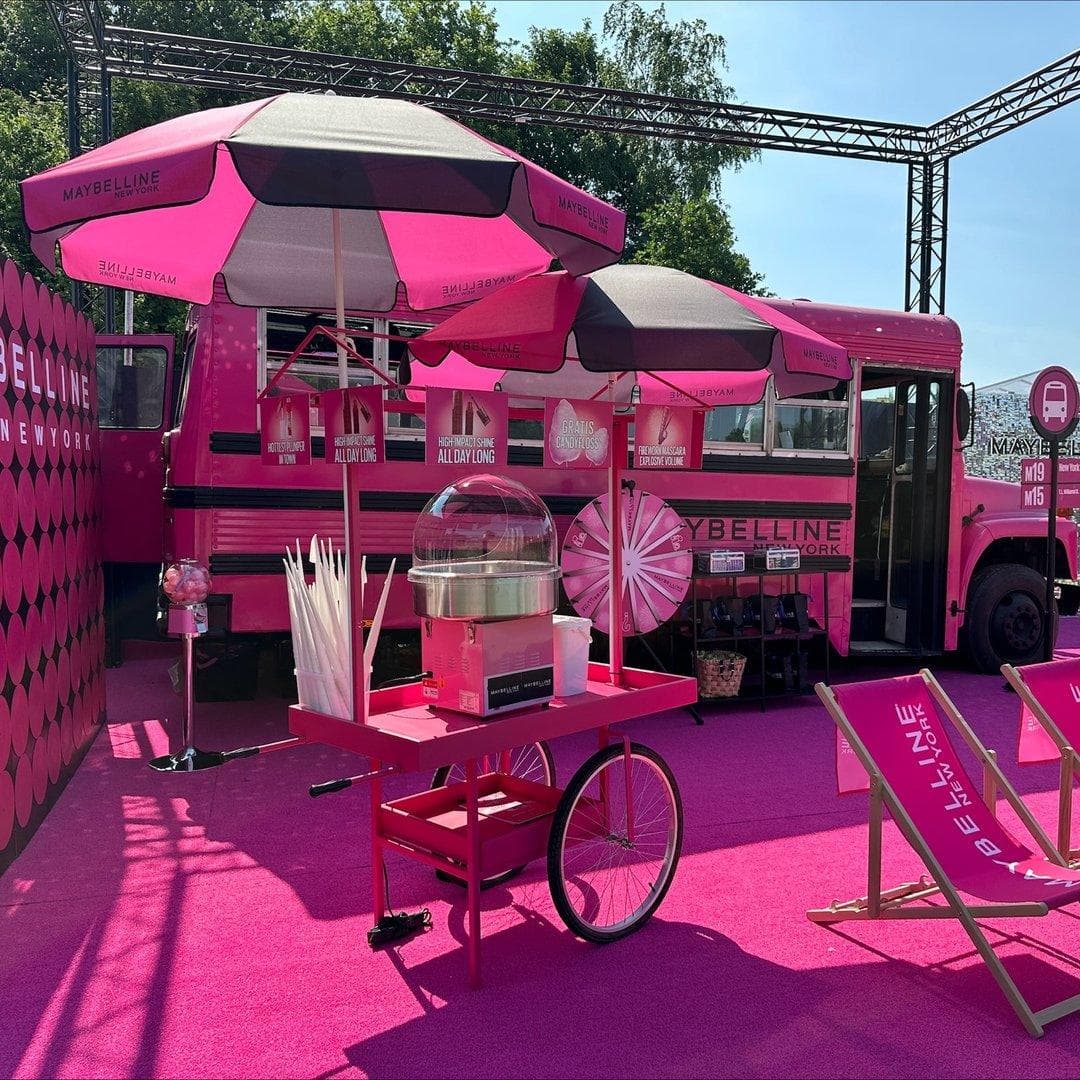 Lyserødt spiseteater med pop-up-telt, møbler og servicekøretøj på gummikloaksmåtte