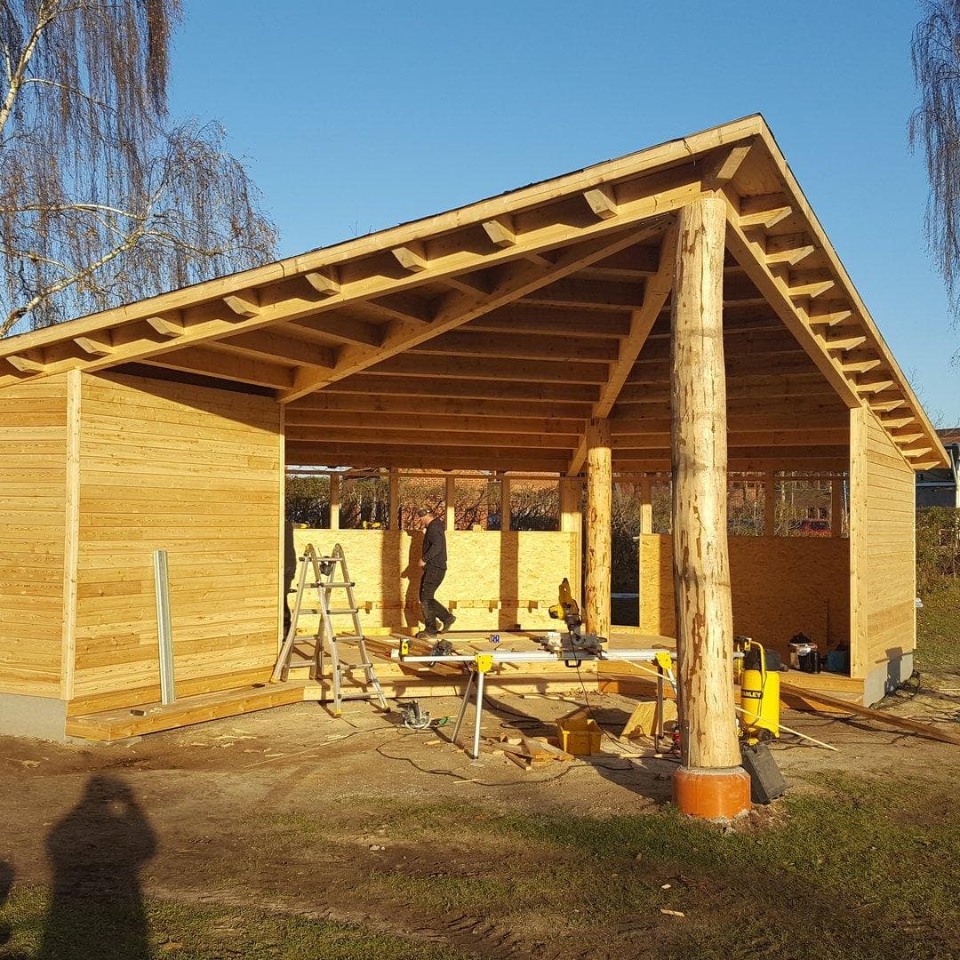 Træhytte i fyr med åben pavillon og betonunderlaget, under konstruktion