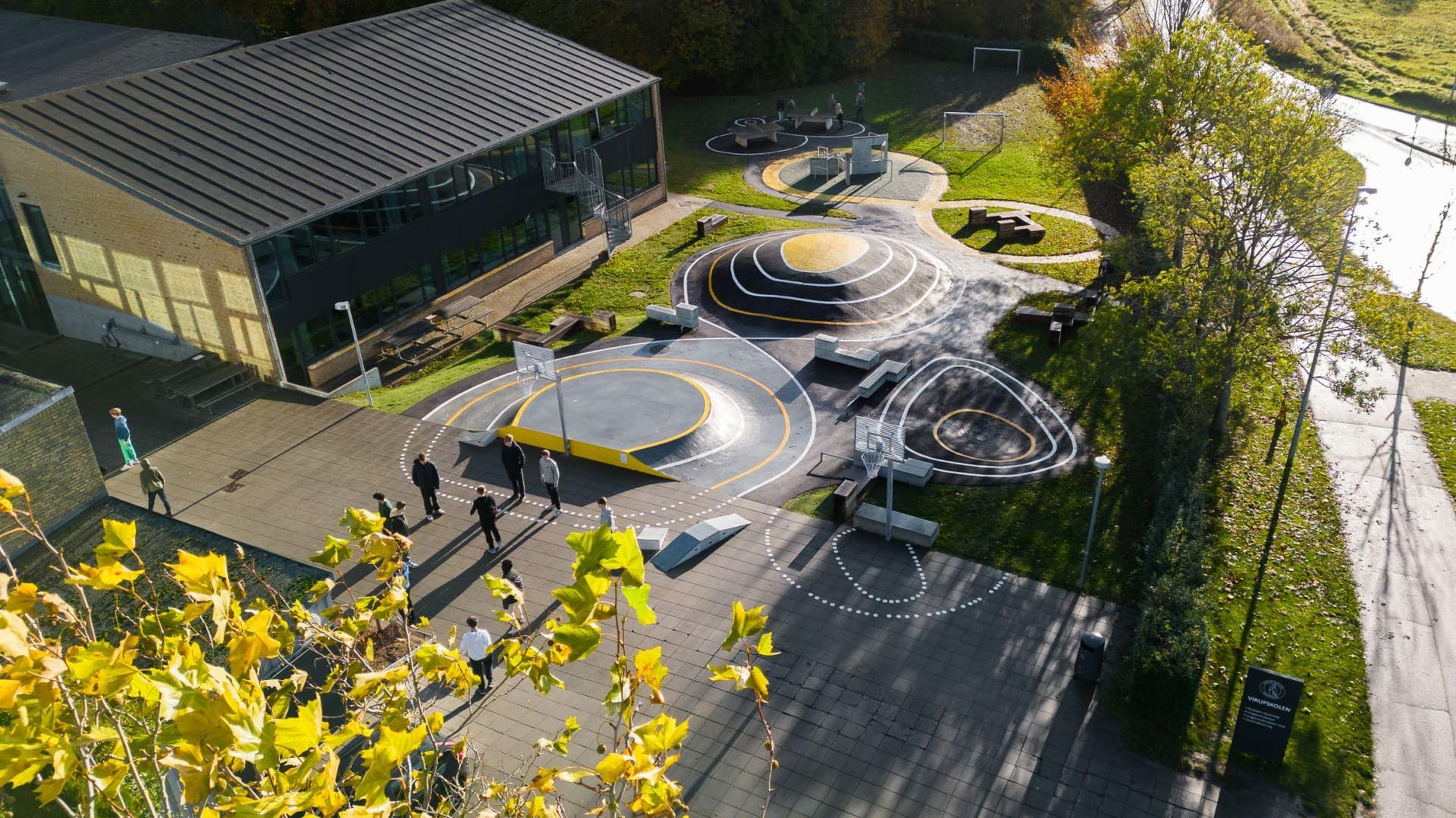 Udeområde med moderne sort asfaltbelægning, spiralformede mønstre og børn samt voksne