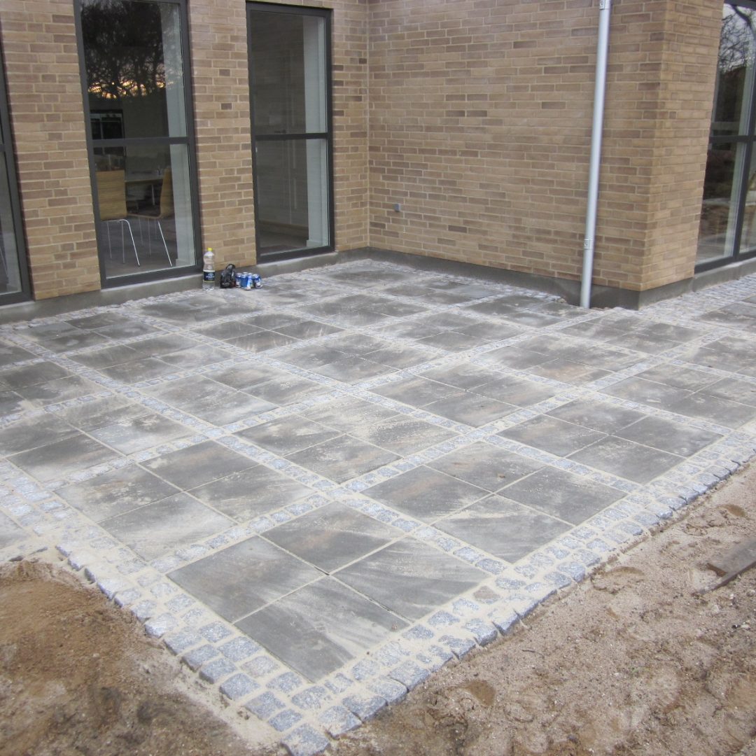 Havefliser med chaussestensbord omkring hus